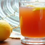 Freshly brewed ginger root tea with honey and lemon on a wooden table in a cozy kitchen.